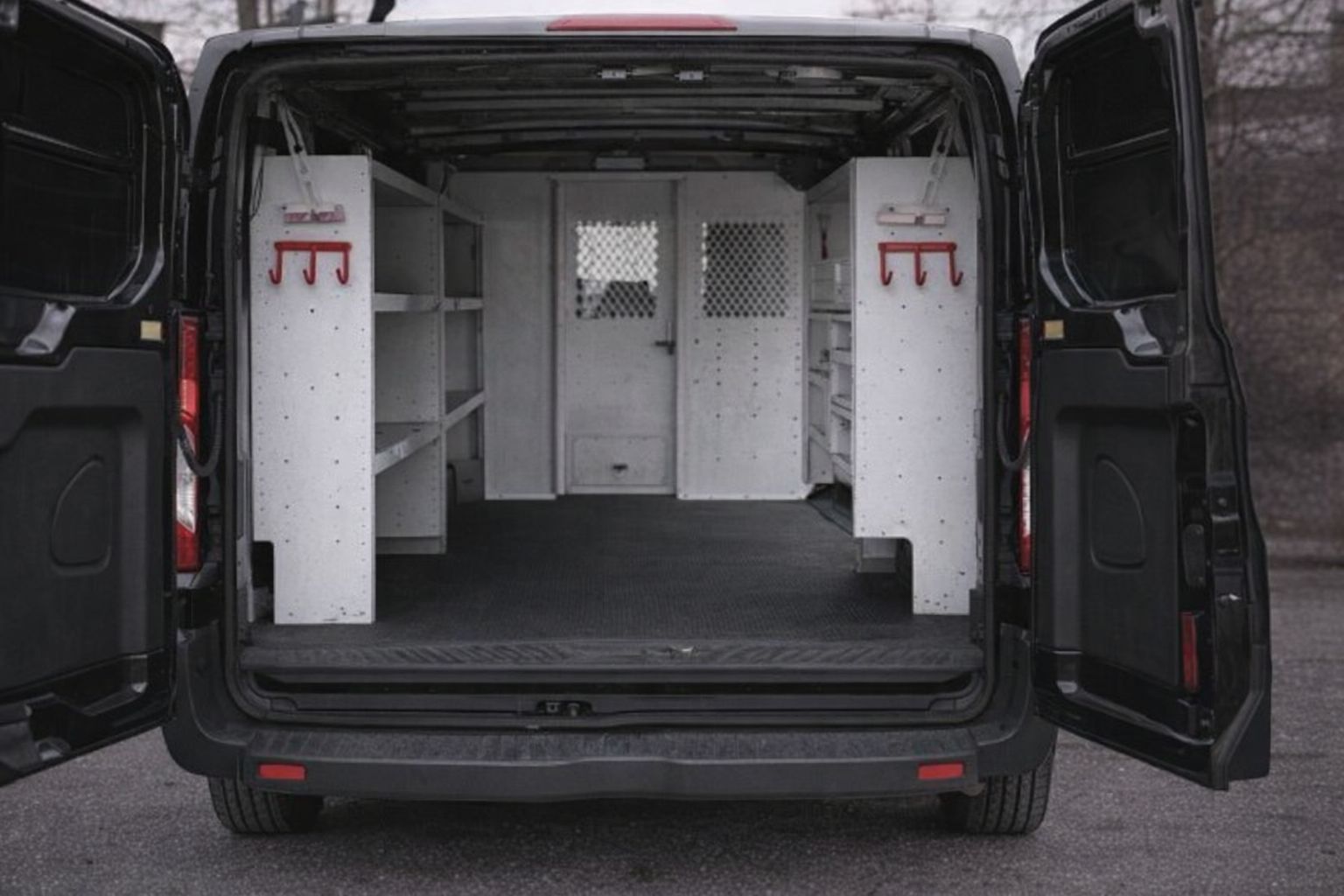 Achterkant van een georganiseerde zwarte werkbus met wit interieur.