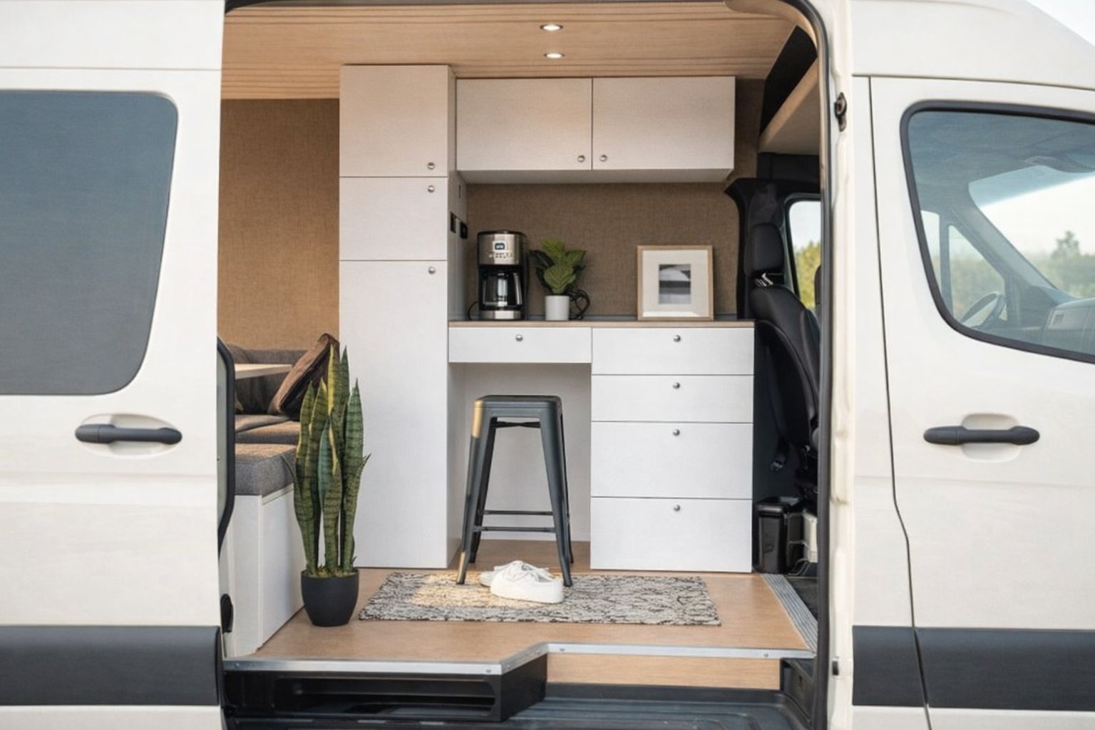 Interieur van een omgebouwde bestelwagen met werkplek en opbergruimte.